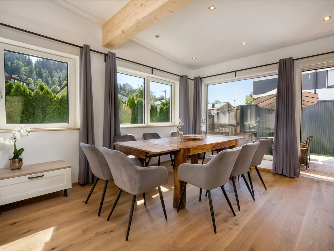 De eettafel voor tien bij de ramen, met het terras en de parasols erachter.
