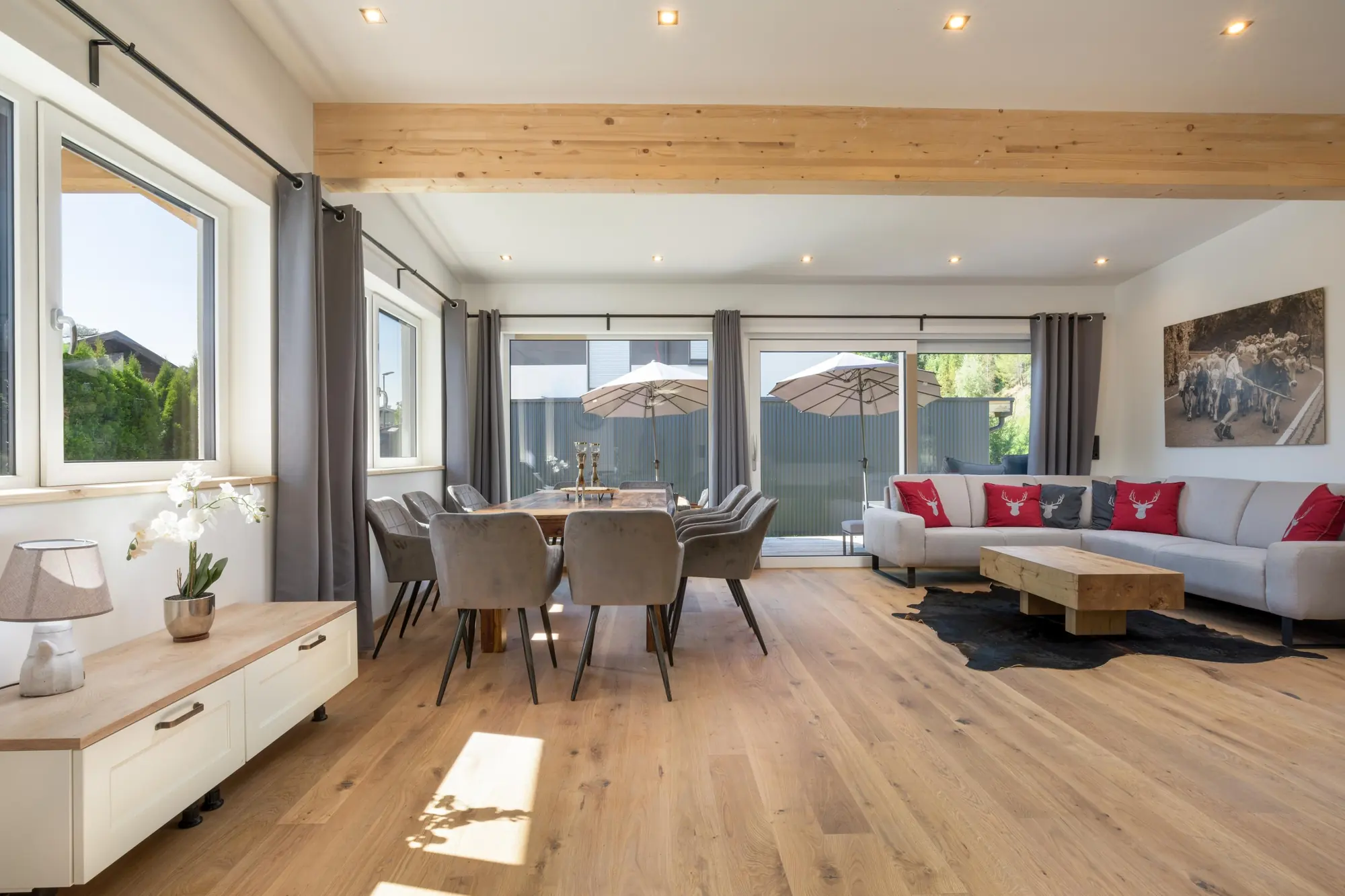 Dezelfde woon- en eetkamer in de zomer, met de eettafel voor tien en parasols op het terras achter het glas.