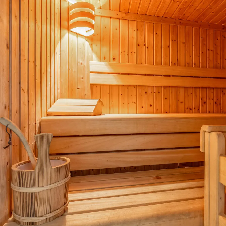 The sauna with wooden benches, a bucket and a ladle.